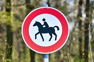 Sign with horse and rider on route for horseback riding in forest,