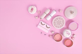 Cute pink makeup beauty products like brushes, powder or lipstick on side of pastel pink background with empty copy space