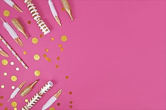 Party flat lay with golden and white decoration like confetti and feathers on pink background with copy space,