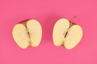 Apple cut into half on pink background,