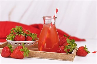 Jar with strawberry fruit lemonade surrounded by berries,