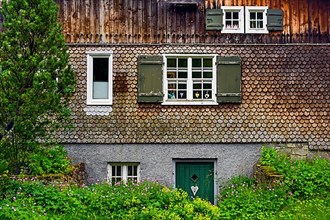 Wooden shingle facade with windows and wild flowers, Hindelang