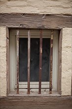 Old window with window grille on a brown house wall with half-timbered beams, Quedlinburg