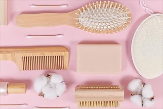 Eco friendly wooden beauty and hygiene products like comb and soap on pink background,