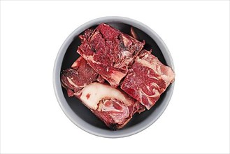 Dog bowl with big red chunks of meat with fat used for raw biologically appropriate feeding on white background,
