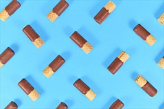 Chocolate glazed waver rolls sweets arranged on blue background,