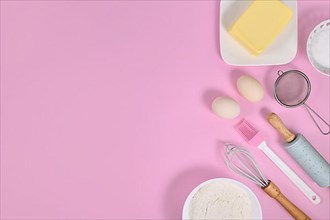 Cake dough ingredients and baking tools on pink background with copy space,