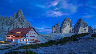 Mountain hut Dreizinnenhuette with rock massif Paternkofel and mountains three peaks at night, Dolomites