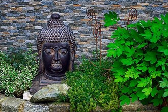 Buddha head in front of wall in front garden, Hindelang