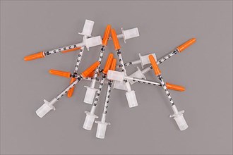 Bunch of small 0, 3 ml U100 insulin syringes used to treat diabetes disease on gray background