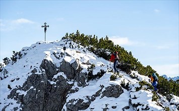 Mountaineers at the summit cross of the Weitalpspitz in winter with snow, Ammergau Alps