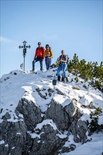 Mountaineer next to summit cross, hiking to Weitalpspitz in the Ammergau Alps