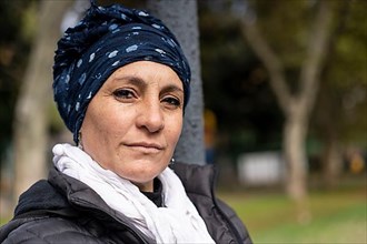 Portrait of a Latin woman undergoing cancer treatment with her head covered by a scarf with an expression of strength,