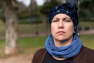 Portrait of a Latin woman undergoing cancer treatment with her head covered by a scarf with an expression of strength,