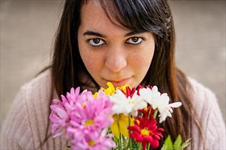 Close-up portrait of a young Latin woman holding a bouquet of flowers,