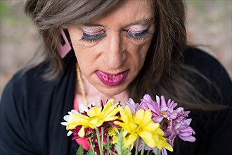 Top view portrait of a mature transgender woman with a bouquet of flowers,
