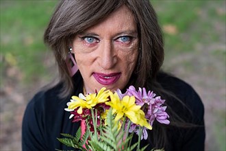Top view portrait of a mature transgender woman with a bouquet of flowers,