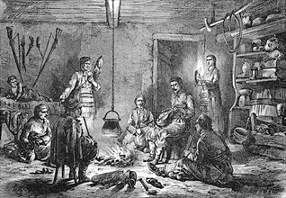 Scene in a farmhouse in Dalmatia, in the kitchen an open fire around which the men sit playing music and smoking