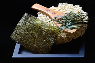 Nori, cut paper-like sheet of seaweed and Asian noodles with chopsticks