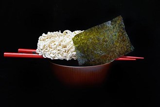 Nori, dried paper-like sheet of seaweed and Asian noodles on a shell