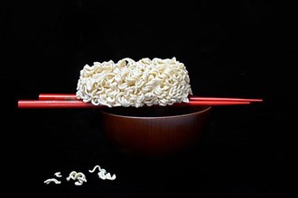 Dried Asian noodles on chopsticks with bowl, pasta