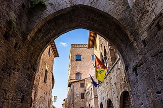 Archway and medieval buildings against a blue sky, San Gimignano