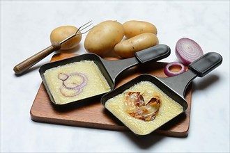 Raclette, melted raclette cheese in pans and ingredients