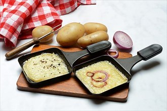 Raclette, melted raclette cheese in pans and ingredients