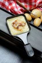 Raclette, melted raclette cheese with bacon in pans and ingredients