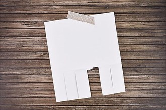 White empty tear-off stub paper note without text on wooden wall,