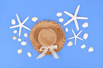 White starfish, seashells and summer straw hat on blue background