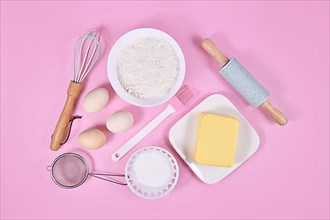 Cake dough ingredients and baking tools on pink background,