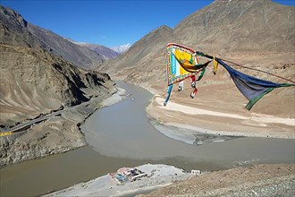 Confluence of the Indus and Zanskar rivers in the Himalayas, prayer flag in front