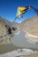 Confluence of the Indus and Zanskar rivers in the Himalayas, prayer flag in front