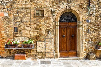 House entrance with round arch front door decorated with flower boxes, Montalcino