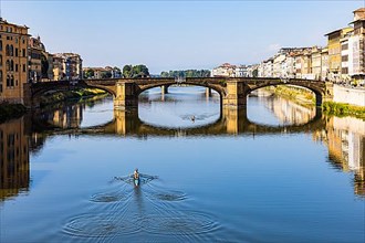 Rowers training on the river Arno, behind the Arno bridge Ponte S. Trinita
