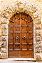 Round arched house entrance door, framed with light-coloured stones