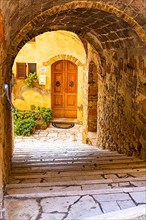 Arched passageway with view of a house entrance door, Petroio