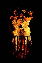 Metal fire basket with burning wood at night,