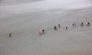 View of the walkers on the mudflats from the monastery hill of Mont Saint-Michel, Lower Normandy