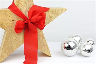 Christmas wooden star with a red bow on a white background, silver Christmas tree balls on the side