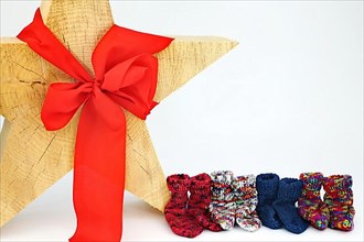 Christmas wooden star with a red bow isolated against a white background, Self-knitted socks on the side