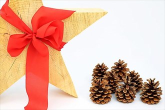 Christmas wooden star with a red bow on a white background, pine cone or pine cone on the side