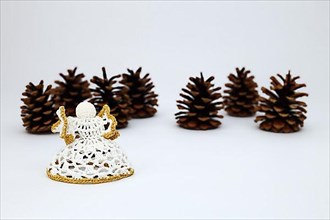 Crochet angel and pine cone or pine cone crocheted against a white background with a sharpening gradient,
