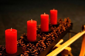 Four Advent candles decorated with pine cones on a sleigh, pre-Advent no candle burning