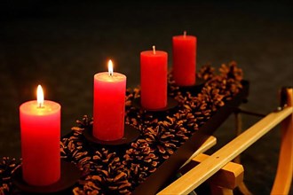 Four Advent candles decorated with pine cones on a sleigh, Second Advent two candles burning
