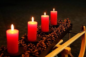 Four Advent candles decorated with pine cones on a sleigh, Fourth Advent four candles burning