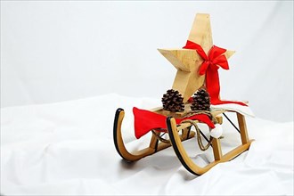 Christmas wooden star with a red bow on a sleigh cut out against a white background,