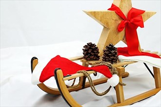 Christmas wooden star with a red bow on a sleigh cut out against a white background,