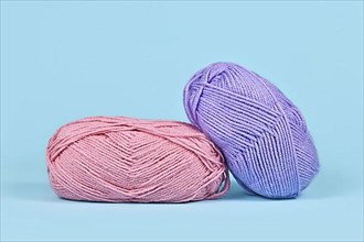 Pink and purple balls of wool on blue background,